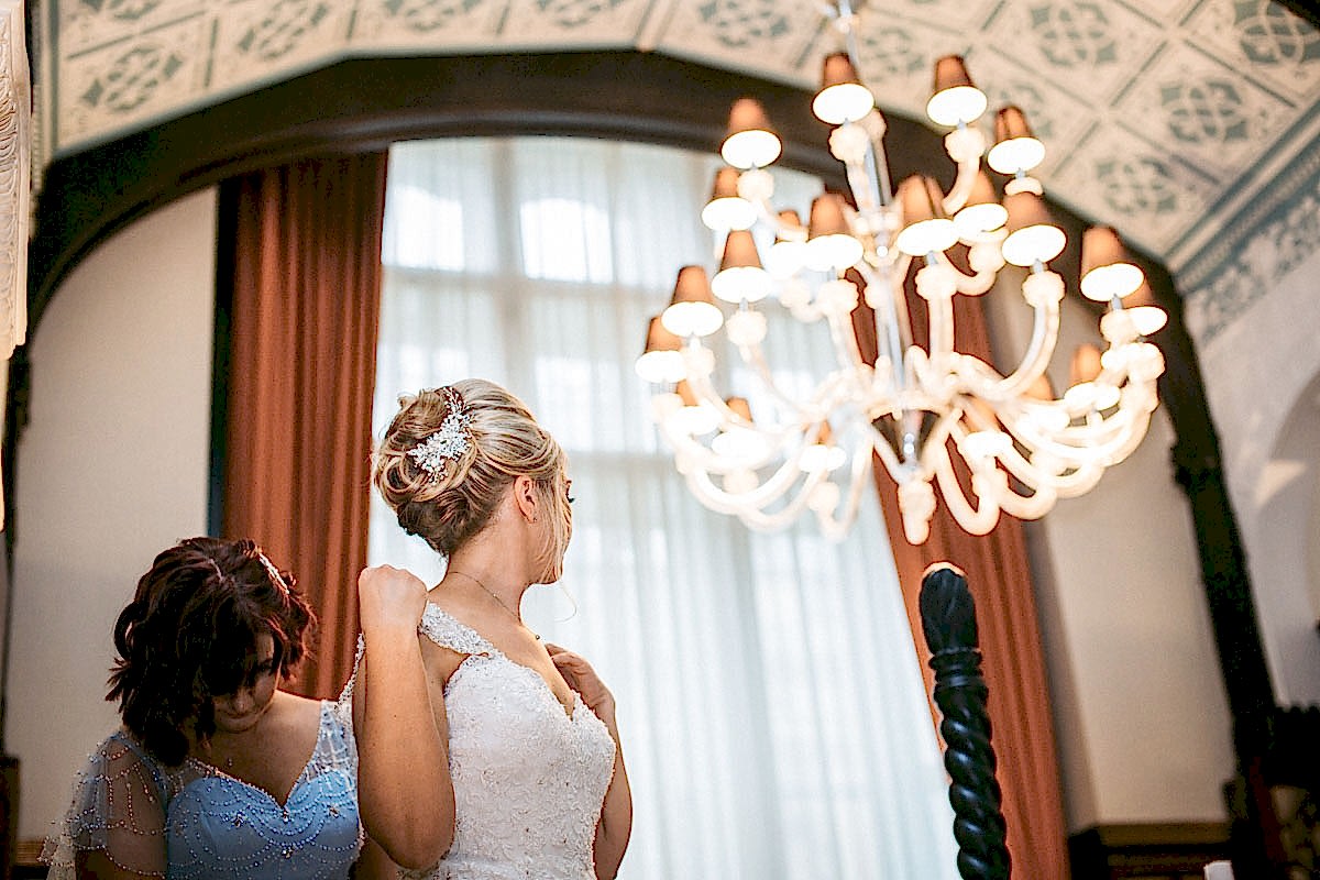 bridesmaid doing up brides dress