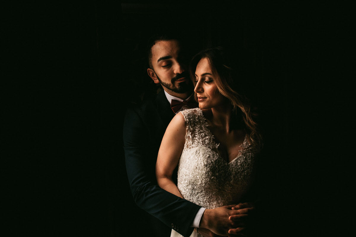bride and groom in very dark room just a black background beautiful photo taken by liverpool wedding photographer