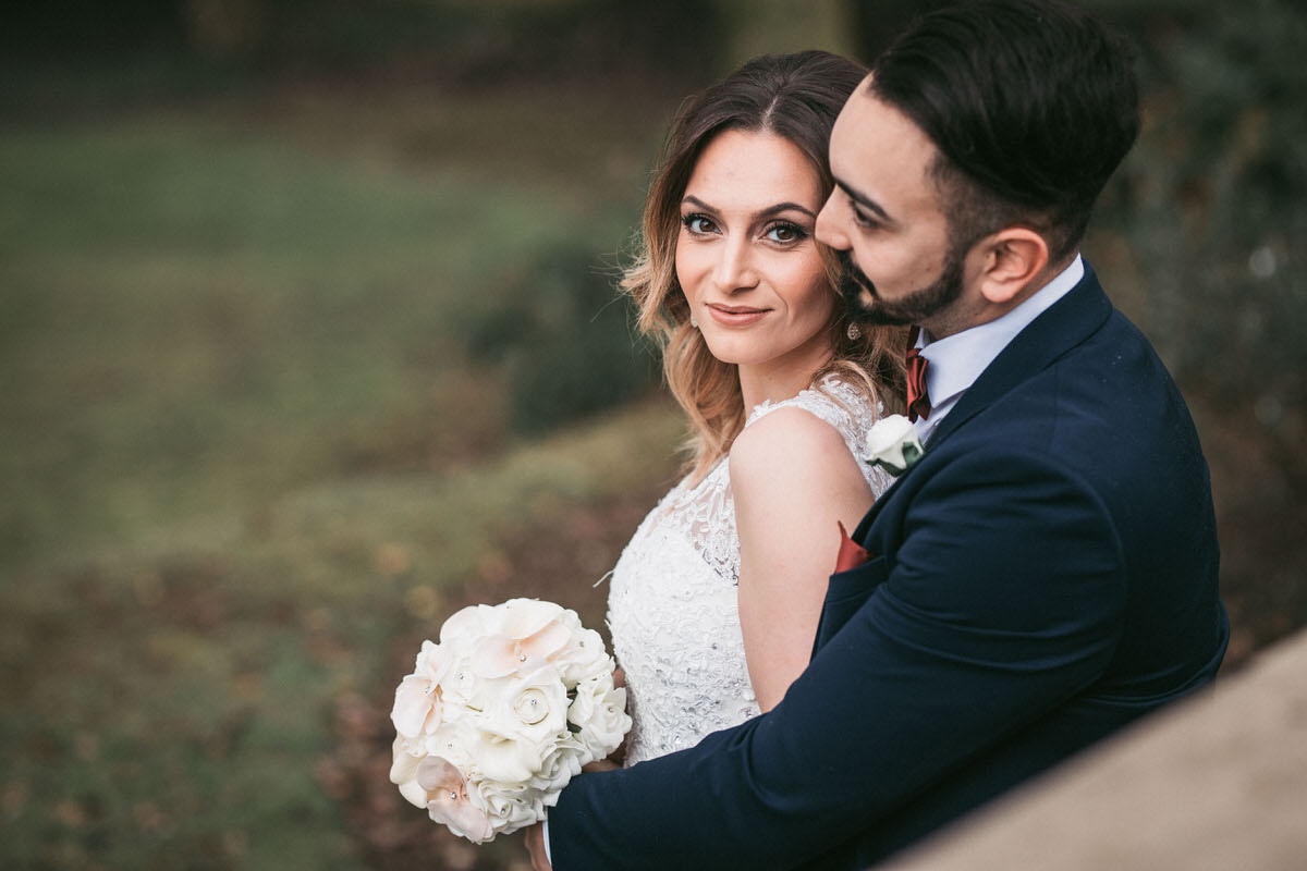 bride looks into camera while groom gives her a hug