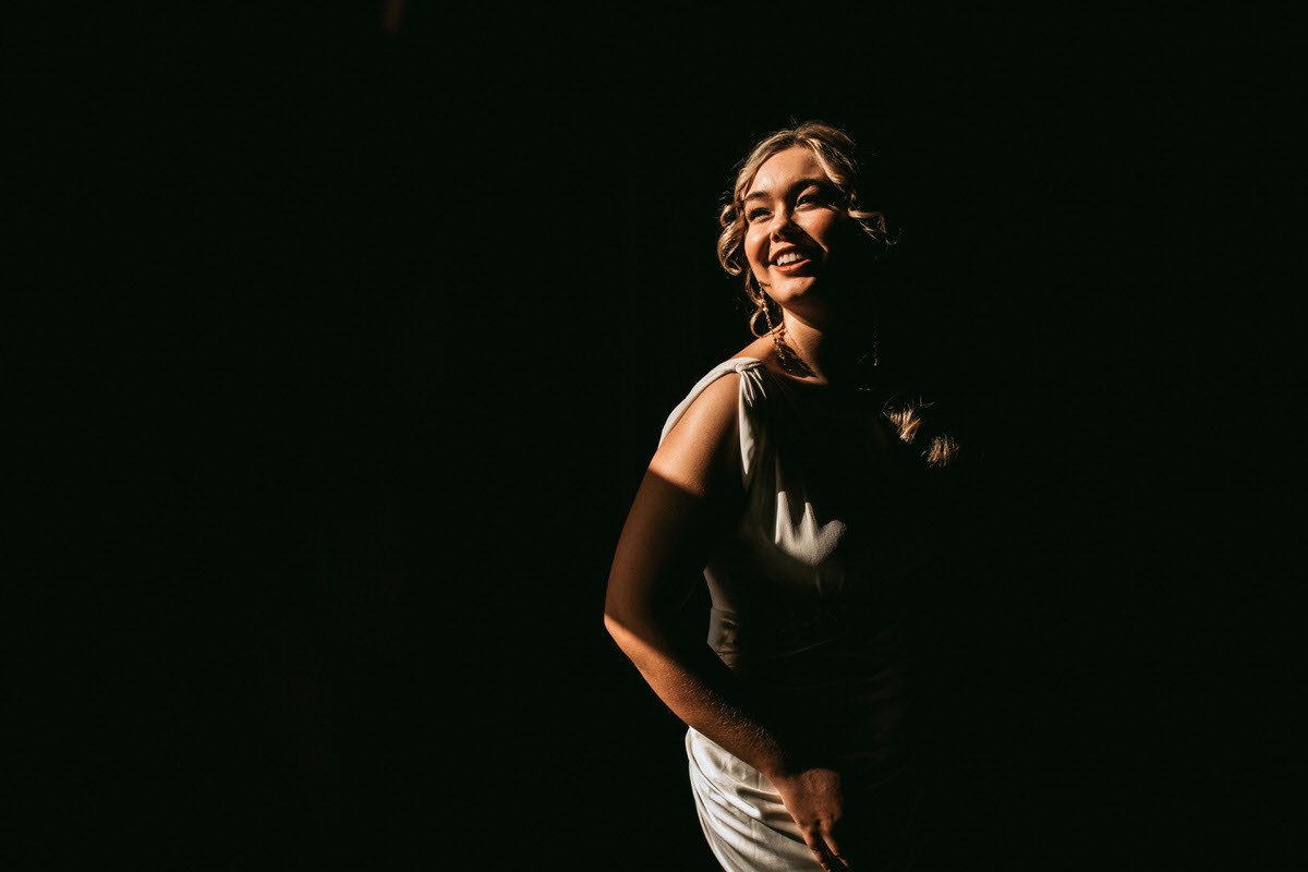 bride laughs while window light shines on her face