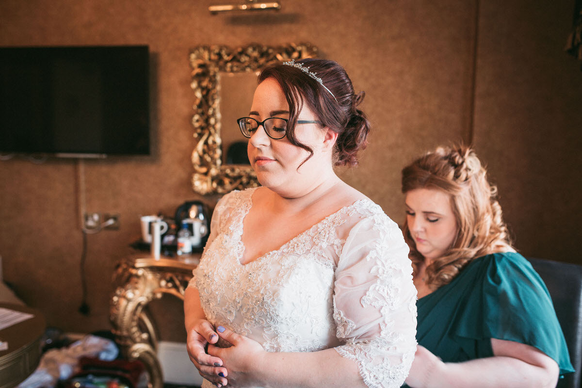 Bride having her dress tied up