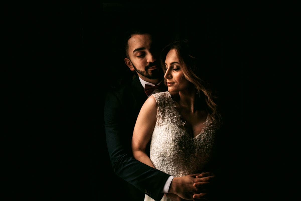 bride and groom in very dark room just a black background beautiful photo taken by liverpool wedding photographer