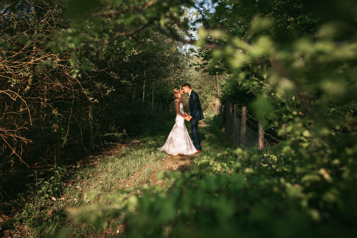 bride and groom kiss in a grassy path way at owen house wedding barn
