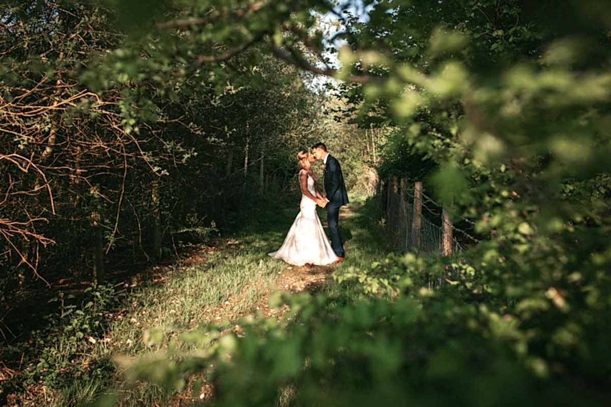 bride and groom kiss in a grassy path way at owen house wedding barn