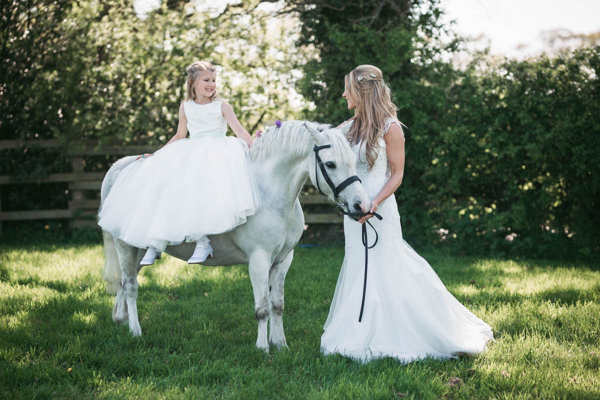 bride and her daughter with their white pony at owen house wedding barn