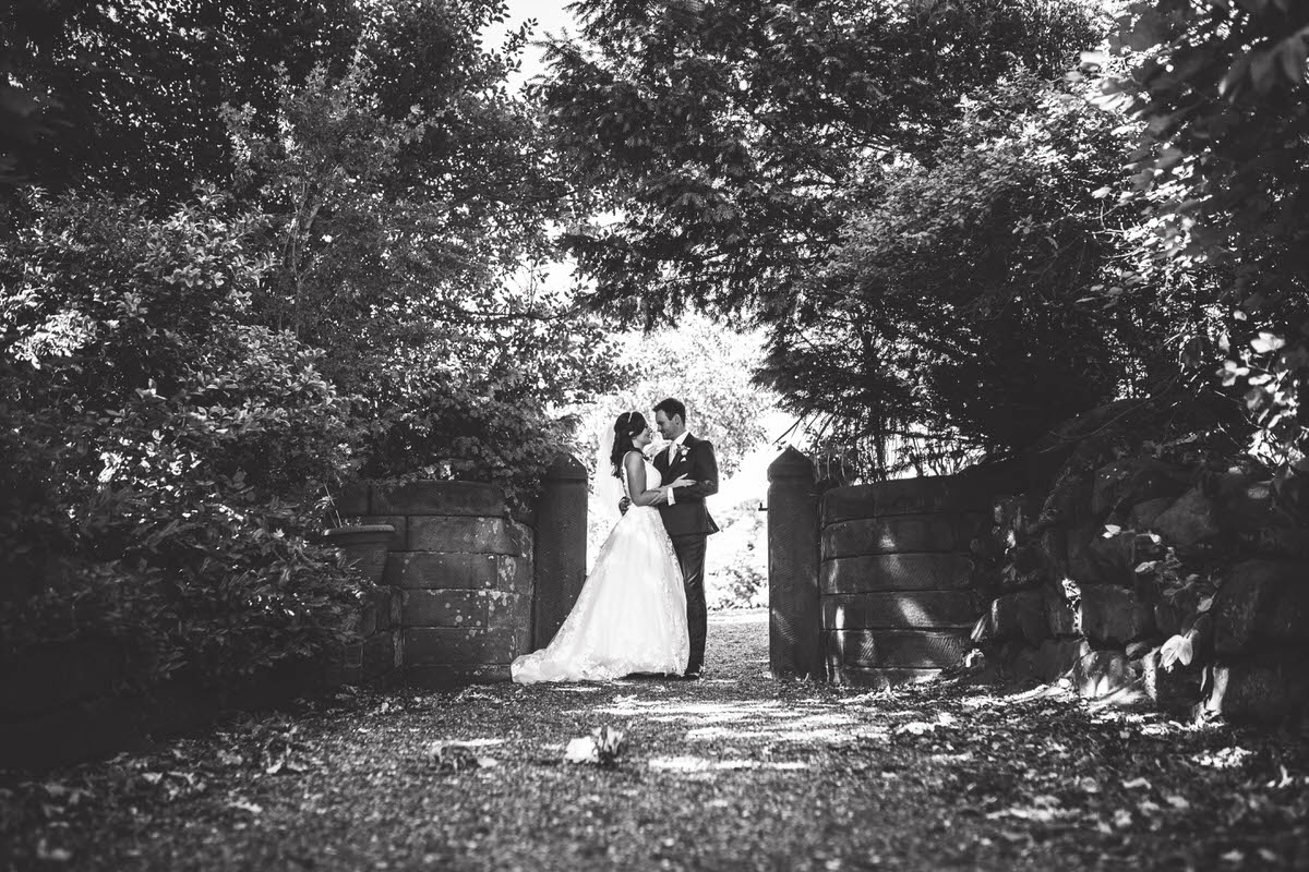 couple photos taken at willington hall in cheshire black and white photo of bride and groom in a gate way