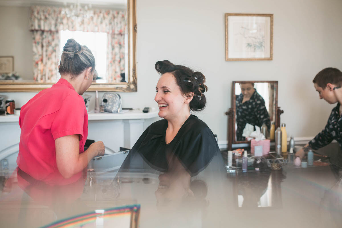 bride laughing whilst getting her make up done at willington hall cheshire phtoography
