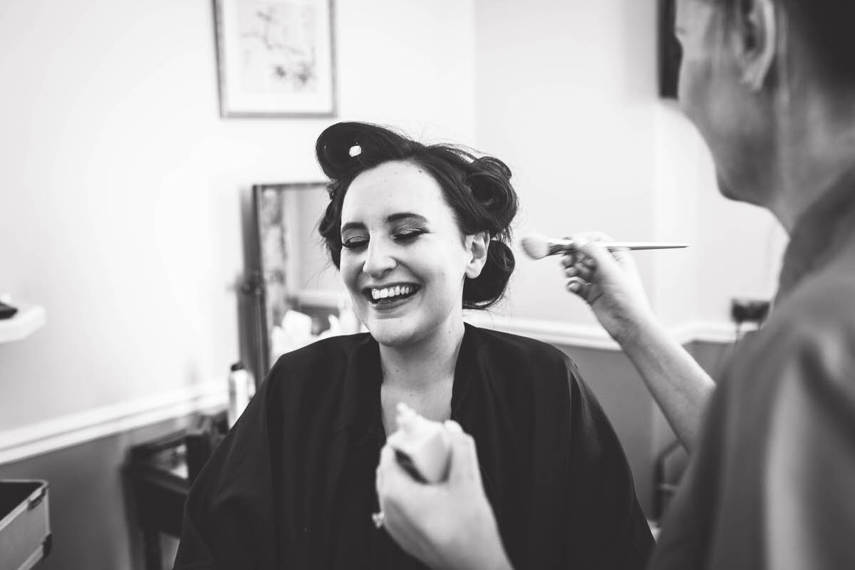 bride laughing whilst getting her make up done at willington hall cheshire phtoography