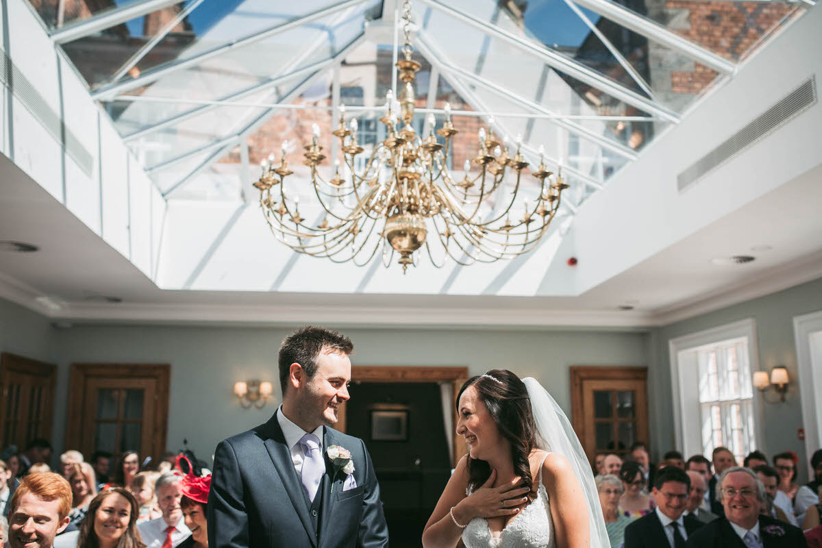 bride and groom during their wedding ceremony at willington hall in cheshire in the orengery