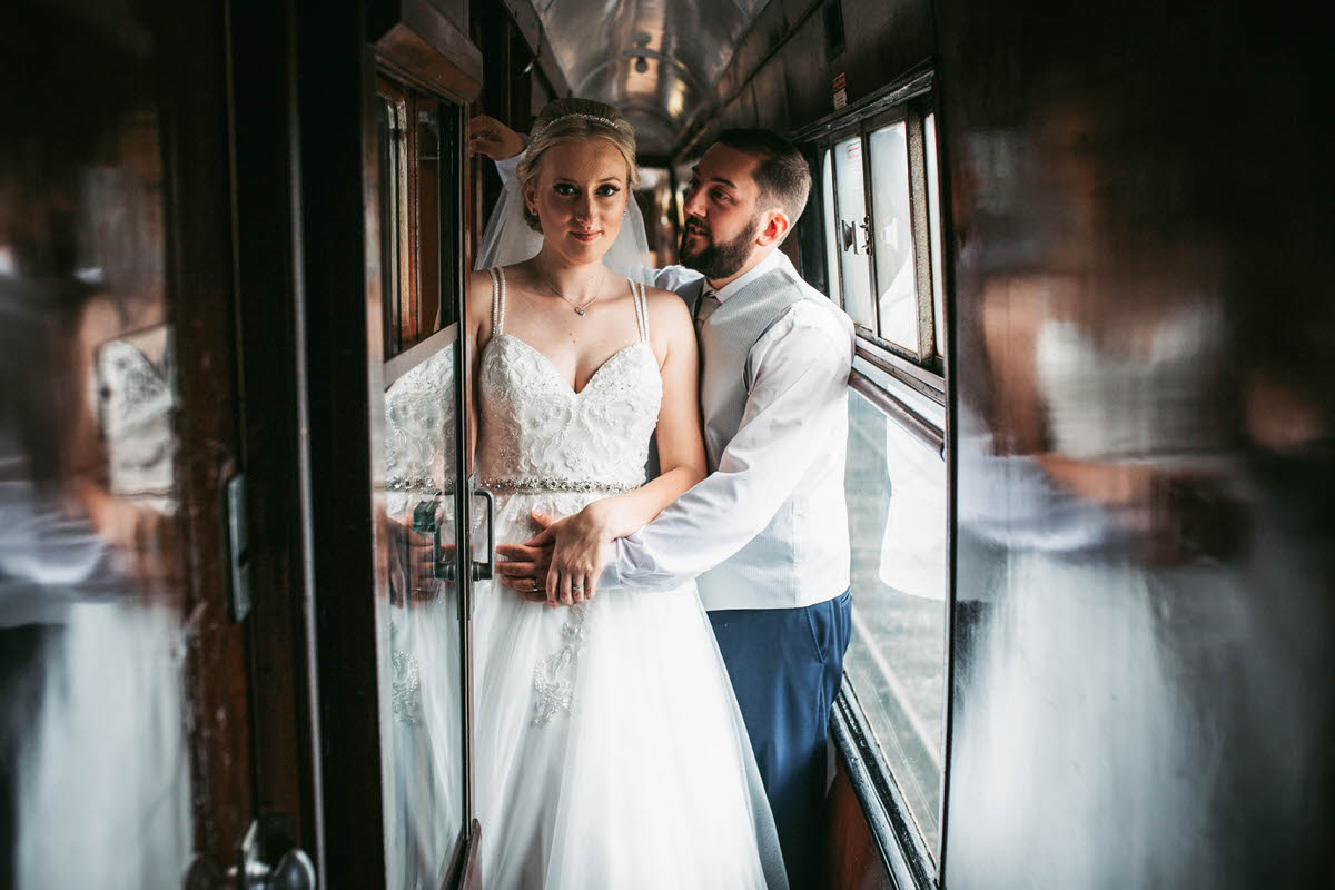 Groom kisses bride in a carriage on the train at llangollen railway station
