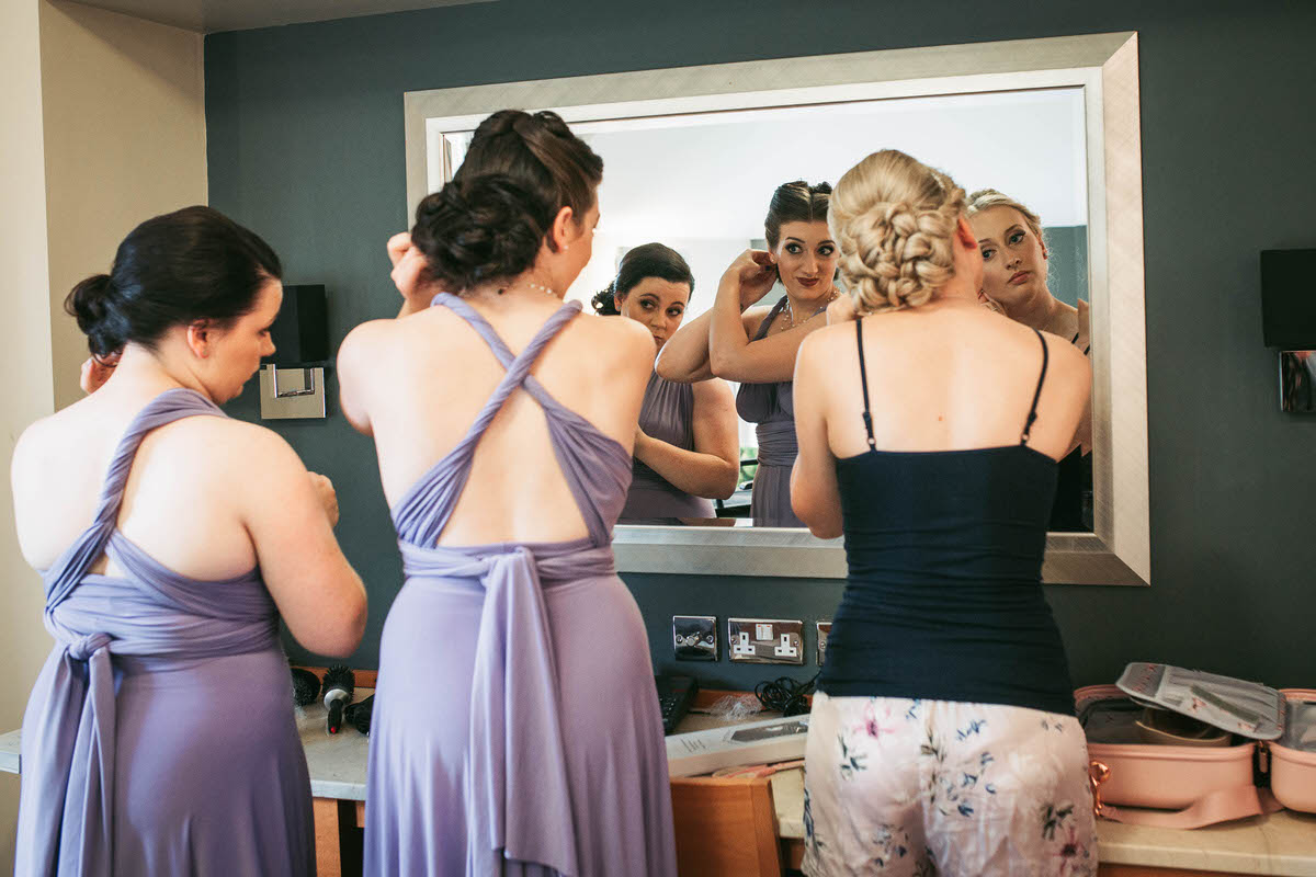 bride and her bridesmaids looking in the mirror geetting ready for the wedding at the wild pheasant hotel llangollen