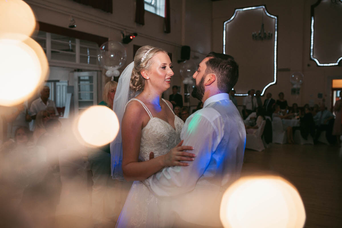 the couple have their first dance together with fairy light effects in corner of frame